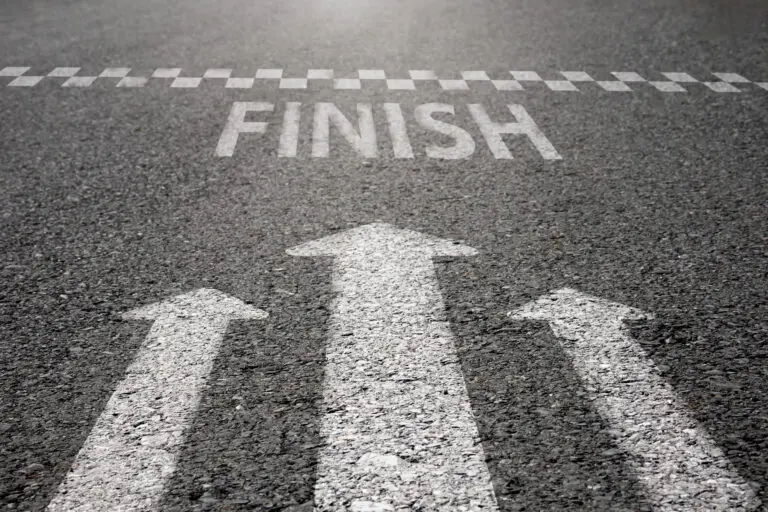 Arrow symbols dash forward to the finish line on the paved road.