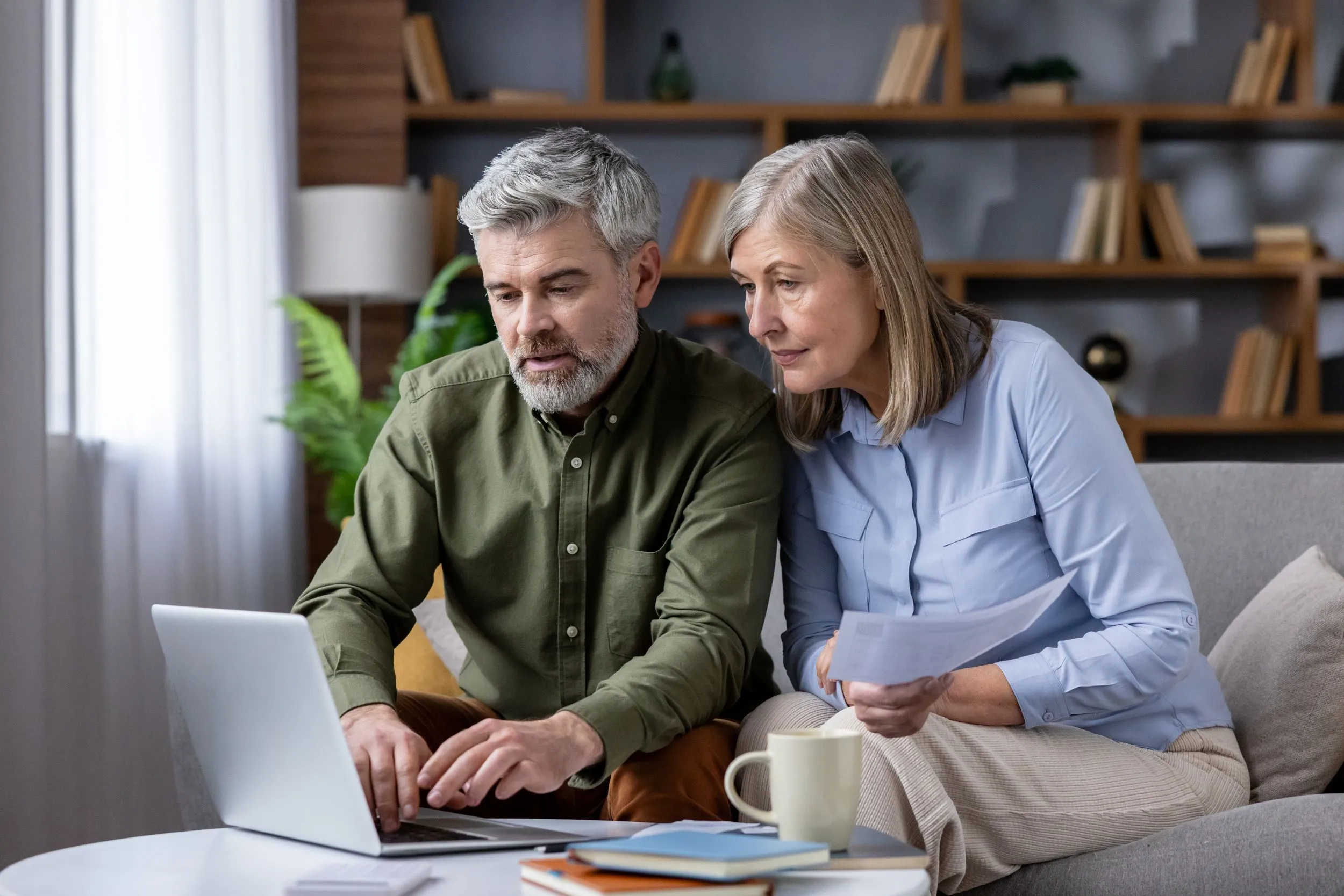 an older couple looks at their finances on a laptop