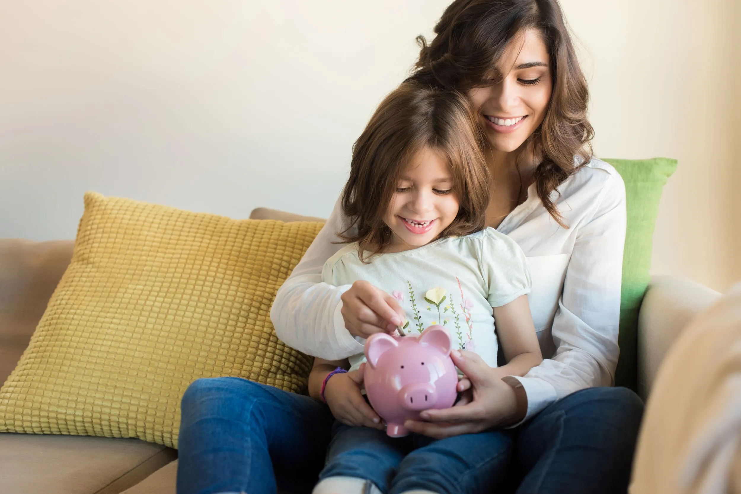 A woman and her child add coins to a piggy bank together